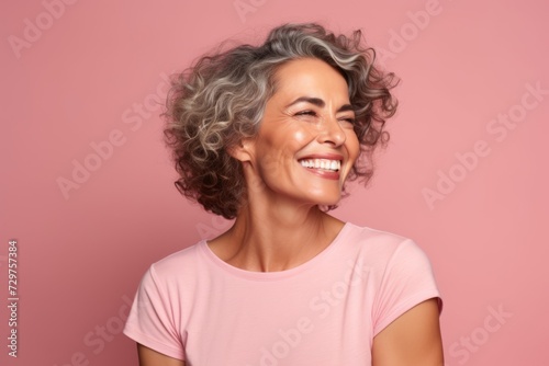 Portrait of smiling middle aged woman with wavy grey hair, isolated on pink background