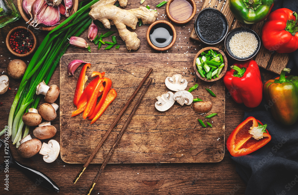 Food and cooking background. Wooden cutting board with chopped vegetables, spices and ingredients for preparing vegetarian Asian dishes with mushrooms and soy sauce. top view, copy space