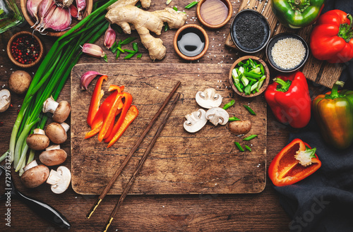 Food and cooking background. Wooden cutting board with chopped vegetables, spices and ingredients for preparing vegetarian Asian dishes with mushrooms and soy sauce. top view, copy space