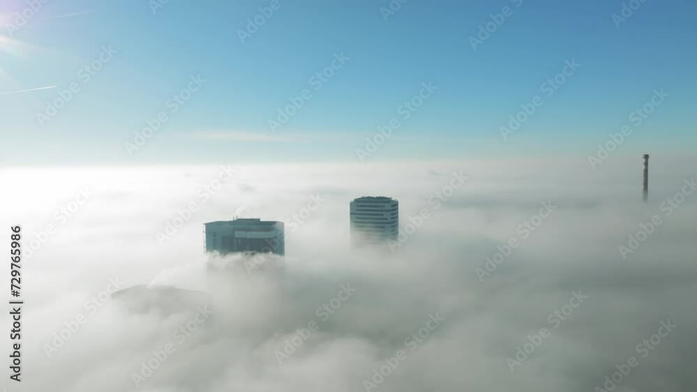 Sunlit aerial journey: Drone gracefully moves forward between towering skyscrapers. Inversion clouds reveal city views, emphasizing the cinematic beauty of urban exploration. LuPa Creative.