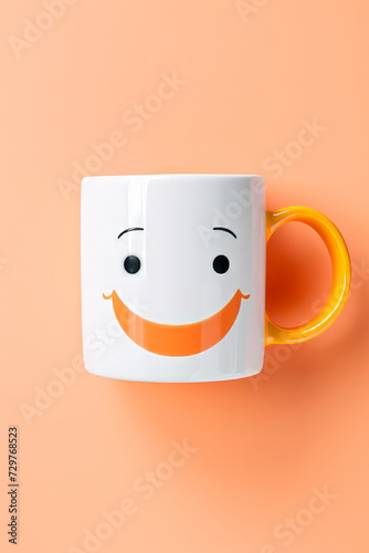 Coffee mug with smiley face on orange background, top view