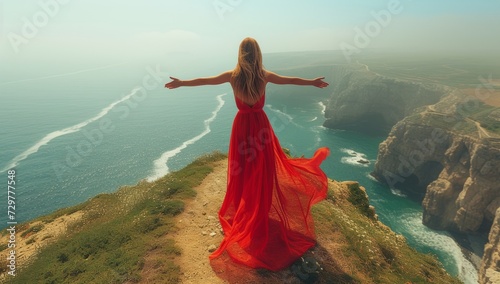 Woman in red dress overlooking sea cliffs