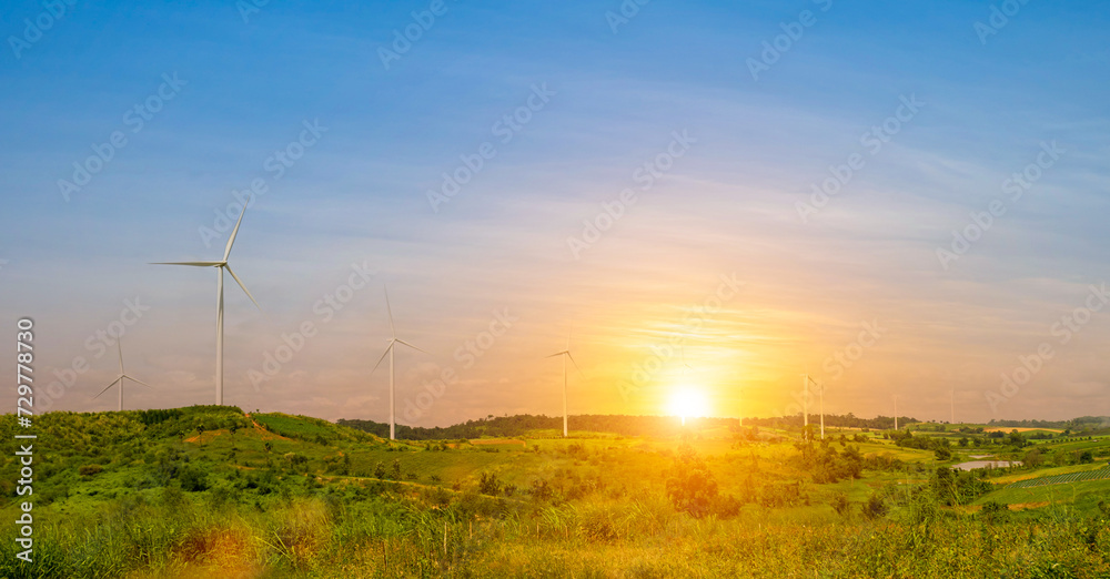 Obraz premium wind turbine with green grass field at beautiful sunset sky background. renewable energy