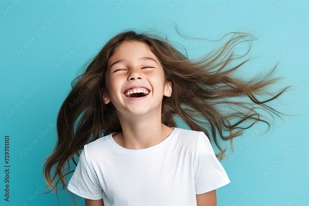 Portrait of a cute little girl with flying hair over blue background Portrait of a cute little girl with flying hair over blue background