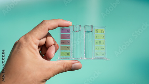 A swimming pool service person is holding a water tester kit which is using for measuring pH value and Chloring concentration. photo