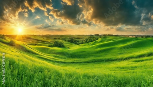 a sunset over a green field  with the sun shining through the clouds and the sun shining through the leaves   wind moving green grass  panoramic view  summer scenery