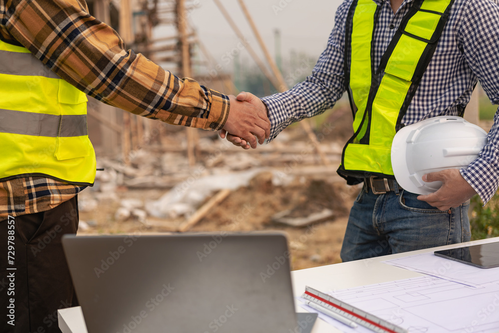 Architect and construction engineer holding hands while working for teamwork and cooperation concept after completing an agreement at office construction site. Architect and construction engineer holding hands while working for teamwork and cooperation concept after completing an agreement at office construction site.
