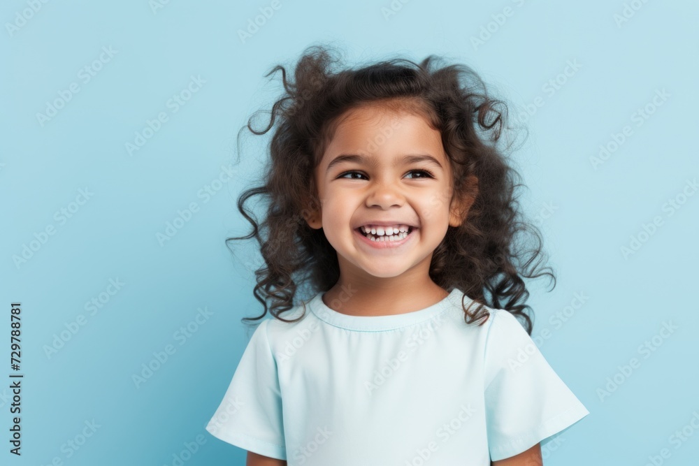 Portrait of a smiling little girl with curly hair on a blue background Portrait of a smiling little girl with curly hair on a blue background