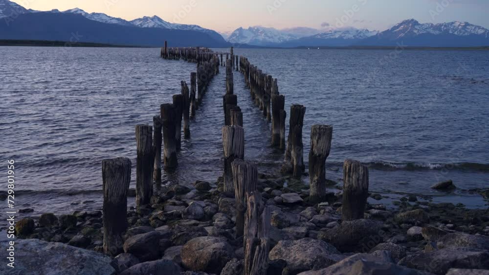 Stakes from an abandoned pier in Puerto Natales, Chile with calm evening waves Stakes from an abandoned pier in Puerto Natales, Chile with calm evening waves