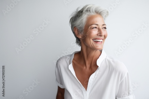 Beautiful mature woman smiling and looking at the camera isolated on grey background