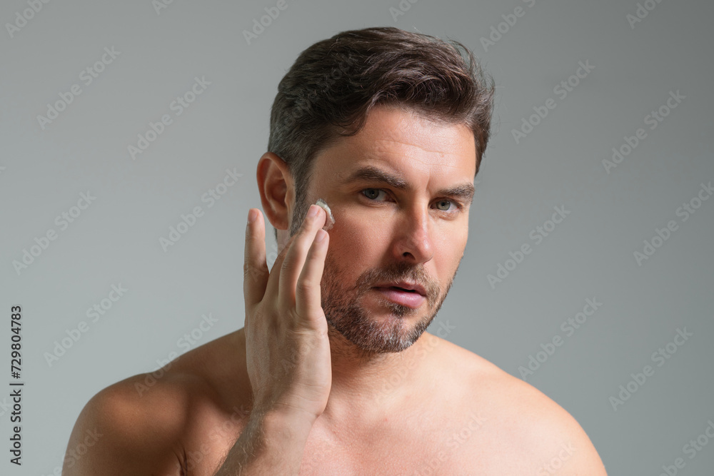 Skincare. Beauty man applying face cream. Male spa model hold face cream. Facial cream, moisturizing lifting nourishing creme. Face cream for skincare. Wrinkle cosmetic facial treatment. Skincare. Beauty man applying face cream. Male spa model hold face cream. Facial cream, moisturizing lifting nourishing creme. Face cream for skincare. Wrinkle cosmetic facial treatment.