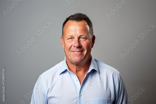 Handsome middle aged man in a blue shirt on a gray background