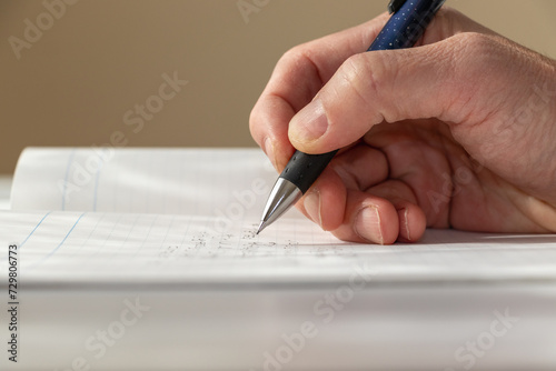 ノートにペンで何か書き込む人の手