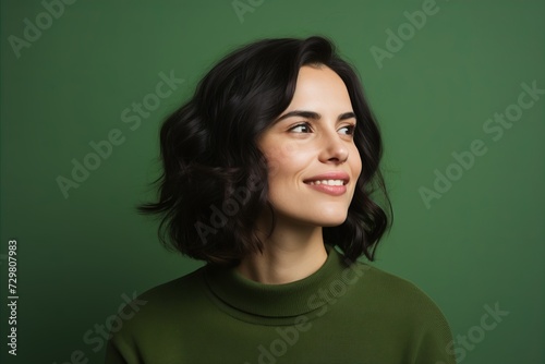 Portrait of a beautiful young brunette woman in a green sweater on a green background