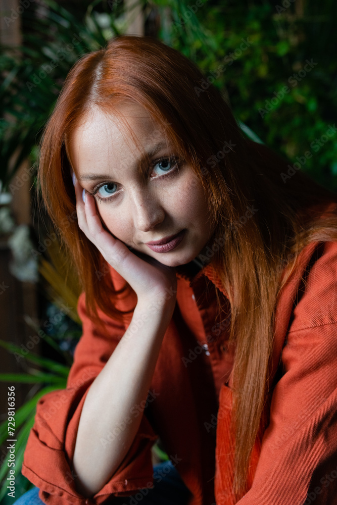 Obraz premium Young red hair woman florist posing at workplace with green potted plants background