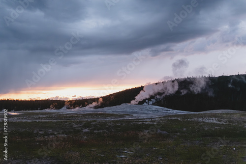 Steam rising from Old Faithful geyser under an overcast sky at sunset in Yellowstone National Park