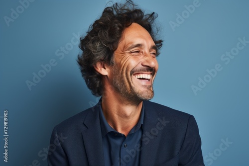 Portrait of a happy man laughing and looking at camera over blue background © Inigo