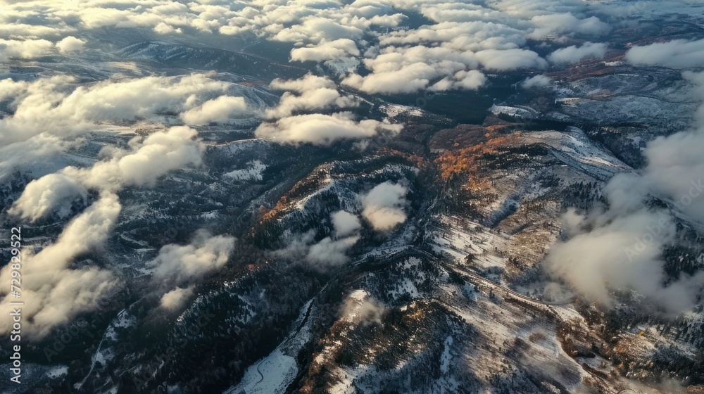  an aerial view of a mountain range with clouds in the foreground and snow on the ground in the foreground, and in the foreground is a blue sky with white clouds.