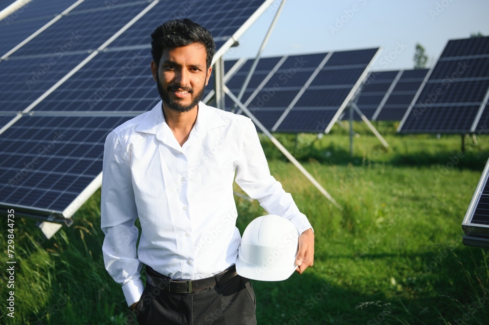 Portrait young indian technician or manager wearing formal cloths standing with solar panel. renewable energy, man standing crossed arm, copy space