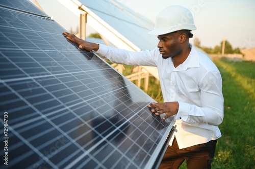 Young African American engineer in a field of solar panels.