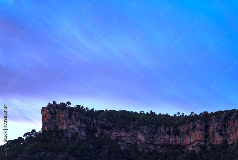 Majestic Cliff Formation Against a Streaked Twilight Sky