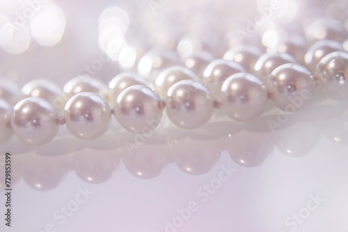 A necklace of pearls lying on white glass 