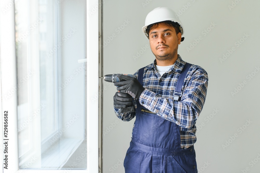 Indian Construction worker installing window in house. Indian Construction worker installing window in house.