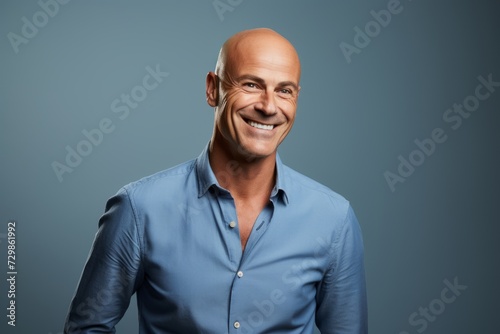 Portrait of a happy mature man in a blue shirt over blue background. © Inigo