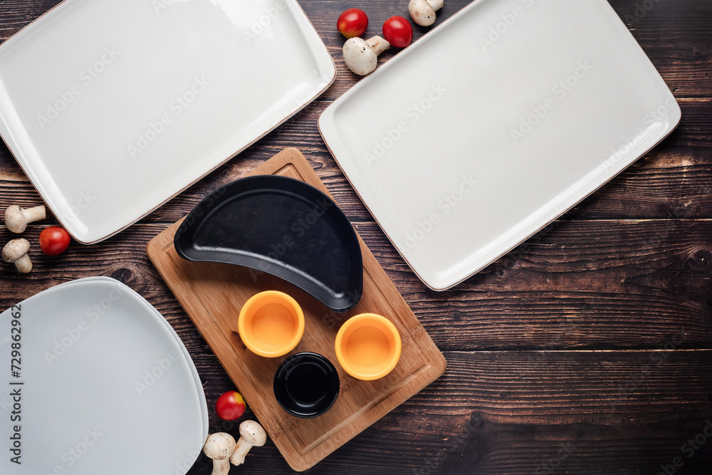 Top view of empty dinner plates with vegetables around them on wooden table Top view of empty dinner plates with vegetables around them on wooden table