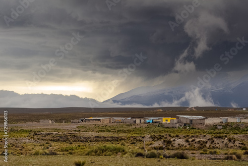 Spectacular landscape in the Peruvian Altiplano in the Andes Mountains between Cabanaconde and Arequipa  Peru. Small village in the pampa. Storm  dramatic sky. Chiaroscuro.