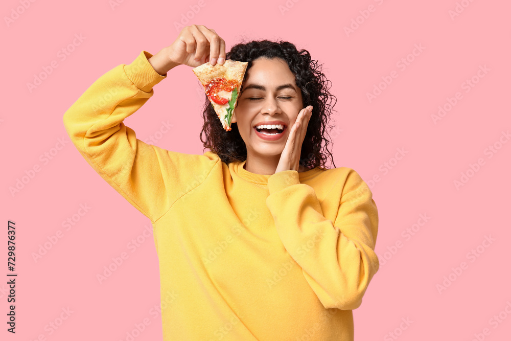 Beautiful young happy African-American woman with slice of delicious pizza on pink background Beautiful young happy African-American woman with slice of delicious pizza on pink background