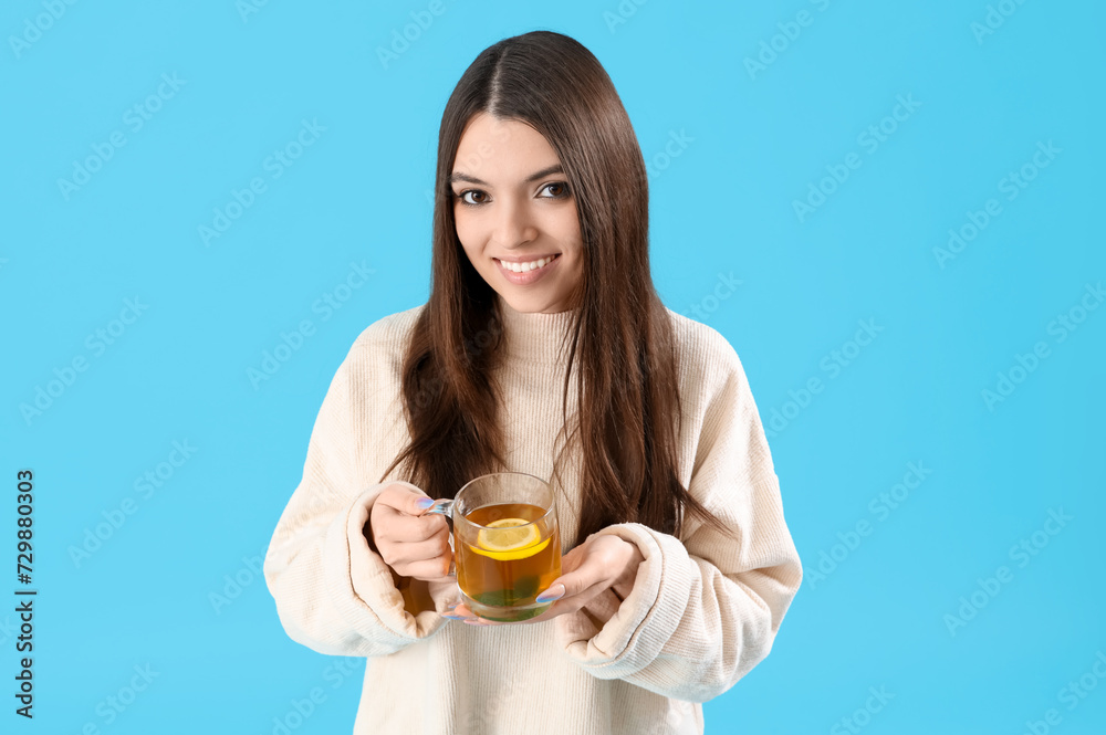 Young woman with glass cup of lemon tea on blue background