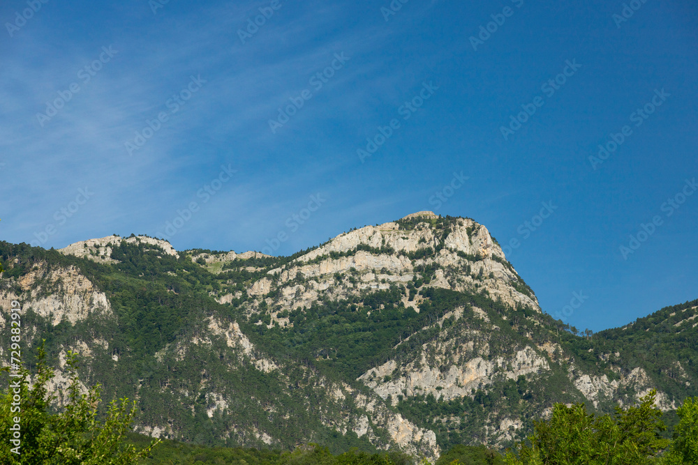 A beautiful morning landscape of a mountain range with a prominent peak against the blue sky. Copy space.