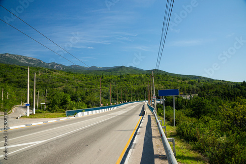 Automobile bridge with an asphalt road passing through a mountain European river.