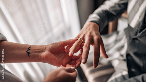 Classic wedding ring on the groom's hand. Wedding ring on the groom's finger. Hand of bride putting wedding ring on groom's finger