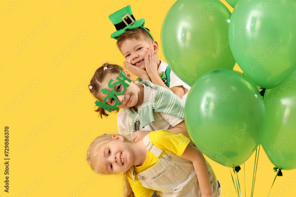 Cute kids with festive green outfits and balloons on yellow background. St. Patrick's Day celebration Cute kids with festive green outfits and balloons on yellow background. St. Patrick's Day celebration
