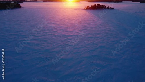 Drone tilting over frozen sea, toward islands and the sunset, winter in Finland photo