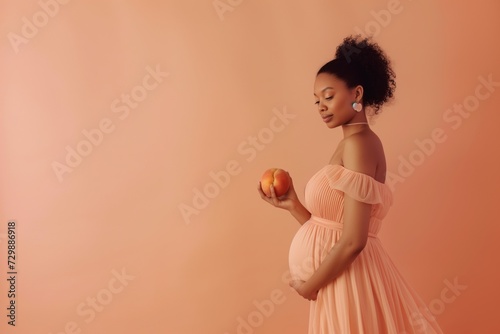 woman in a peach dress holding a peach against peach backdrop © primopiano
