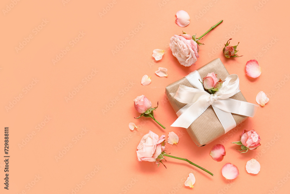 Gift box with roses and petals on orange background