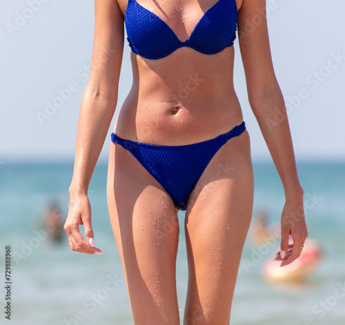Girl in a blue swimsuit on the sea beach