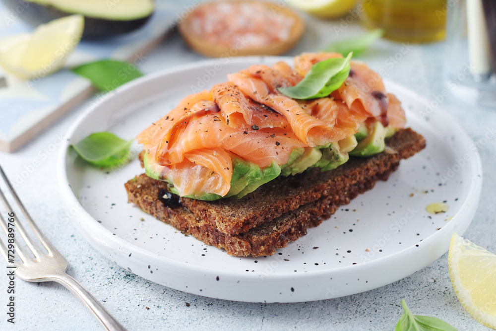 A rye bread sandwich with avocado and salmon