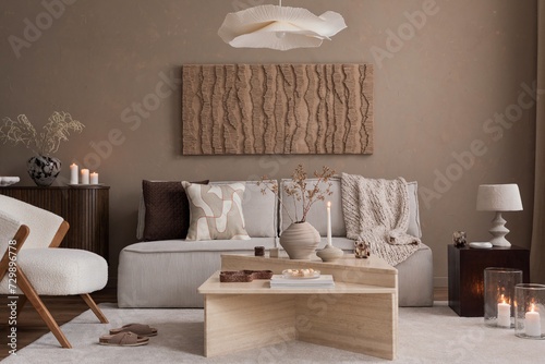 Modern composition of japandi interior with design beige sofa  natural colors paintings  stone tables  stylish furniture  decoration and personal accessories. Home decor. Template.  