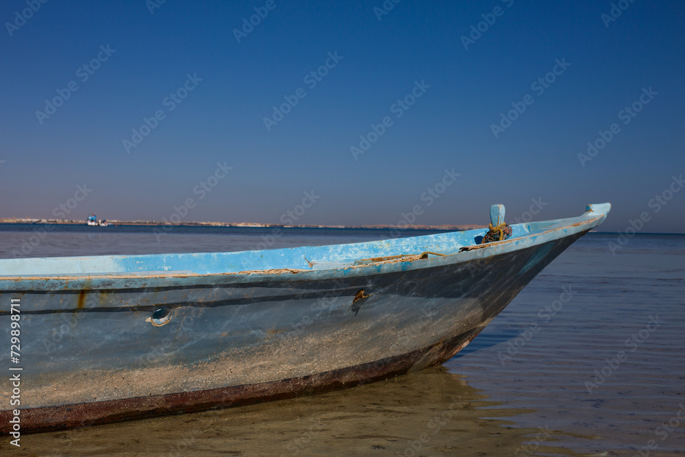 Old ship rusts in shallow water. Abandoned fishing boat at sea
