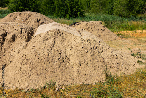 A mountain of sand on a construction site. Foundation material. The soil is prepared to strengthen the soil. Earth heap. Fine sand for leveling and backfilling