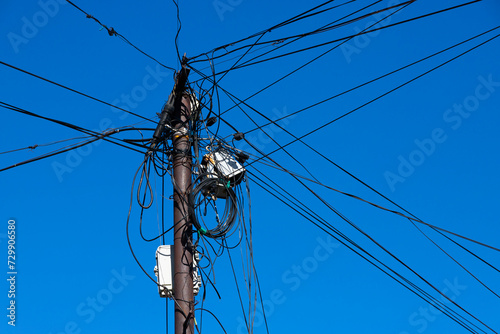 Internet, wires and cable on a distribution pole on the street against the blue sky. photo