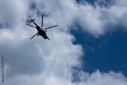 Military Russian helicopter flies in the blue sky with clouds. Bottom view. selective focus