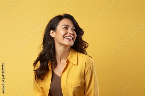 Portrait of happy asian woman in yellow jacket on yellow background © Inigo