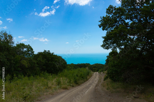 Mountain country road leading to the sea from a milestone to the bottom against the sky.