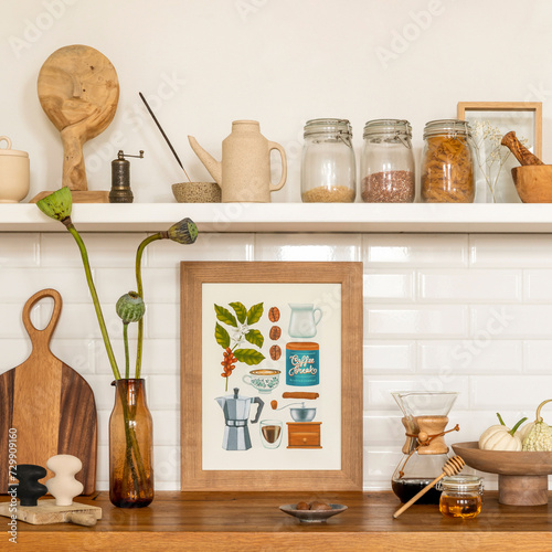 Cozy composition of kitchen interior with mock up poster frame, vase with flowers, white tile, wooden countertop, jar with spices, silver oven, vegetable and personal accessories. Home decor. Template