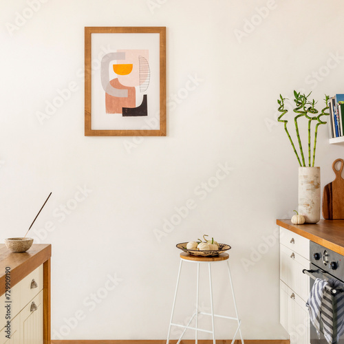 Minimalist composition of kitchen interior with mock up poster frame, white kitchen furniture, wooden kitchen island, induction hob, stool with bowl, pear and personal accessories. Home decor Template